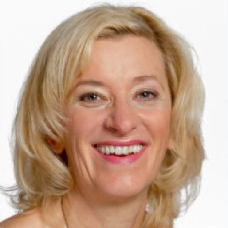 Lächelnde Frau mit blonden Haaren und leicht gerafftem Oberteil, freundlicher Ausdruck.