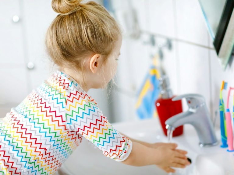 Kleines Mädchen wäscht die Hände am Waschbecken.