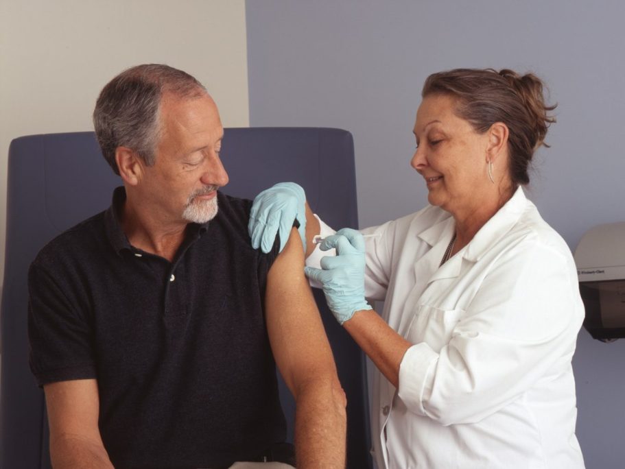 Älterer Mann erhält eine Impfung von einer Krankenschwester.