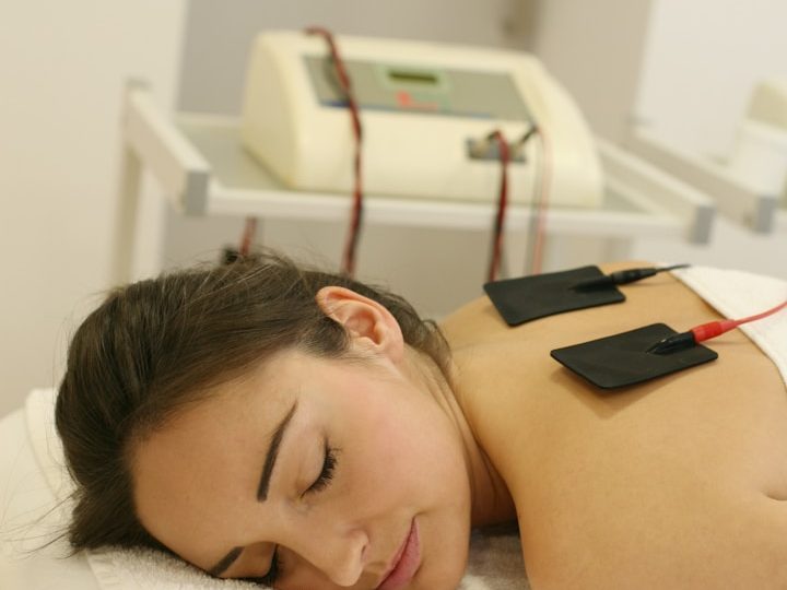 Frau liegt entspannt auf einer Liege mit Elektroden auf dem Rücken.
